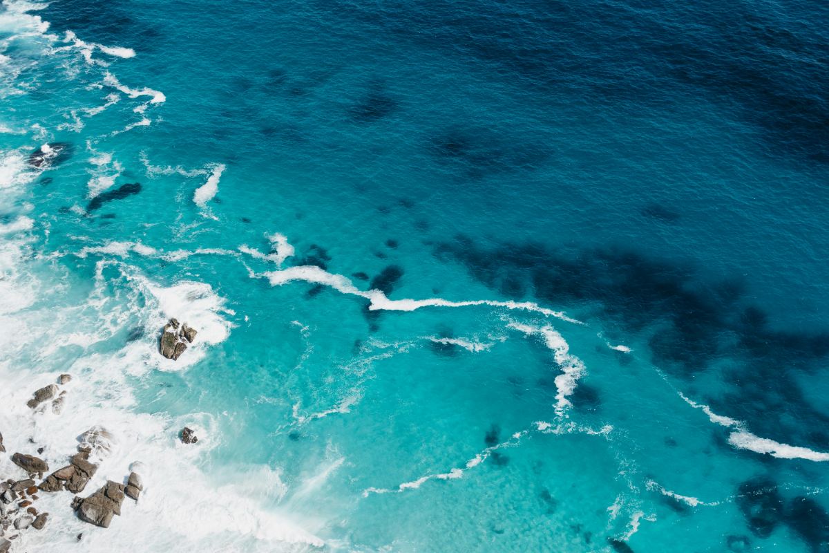 Aerial view of turquoise water meeting a rocky shoreline