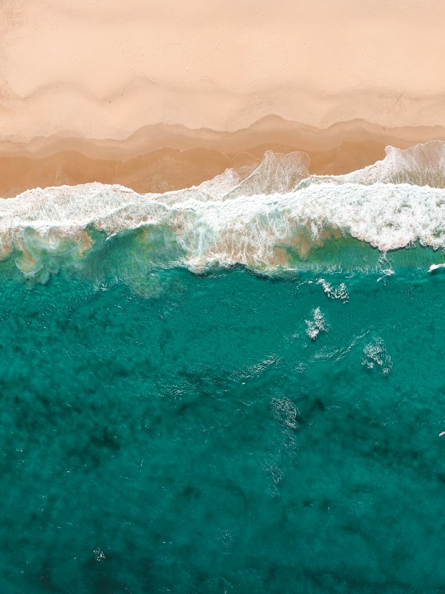 Aerial view of waves breaking onto a sandy shore
