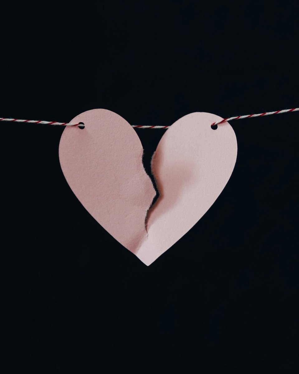 A paper heart, torn in two, hanging from a string