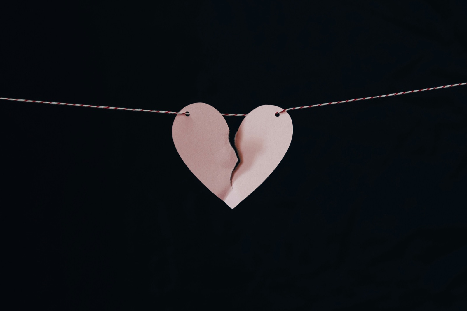 A paper heart, torn in two, hanging from a string