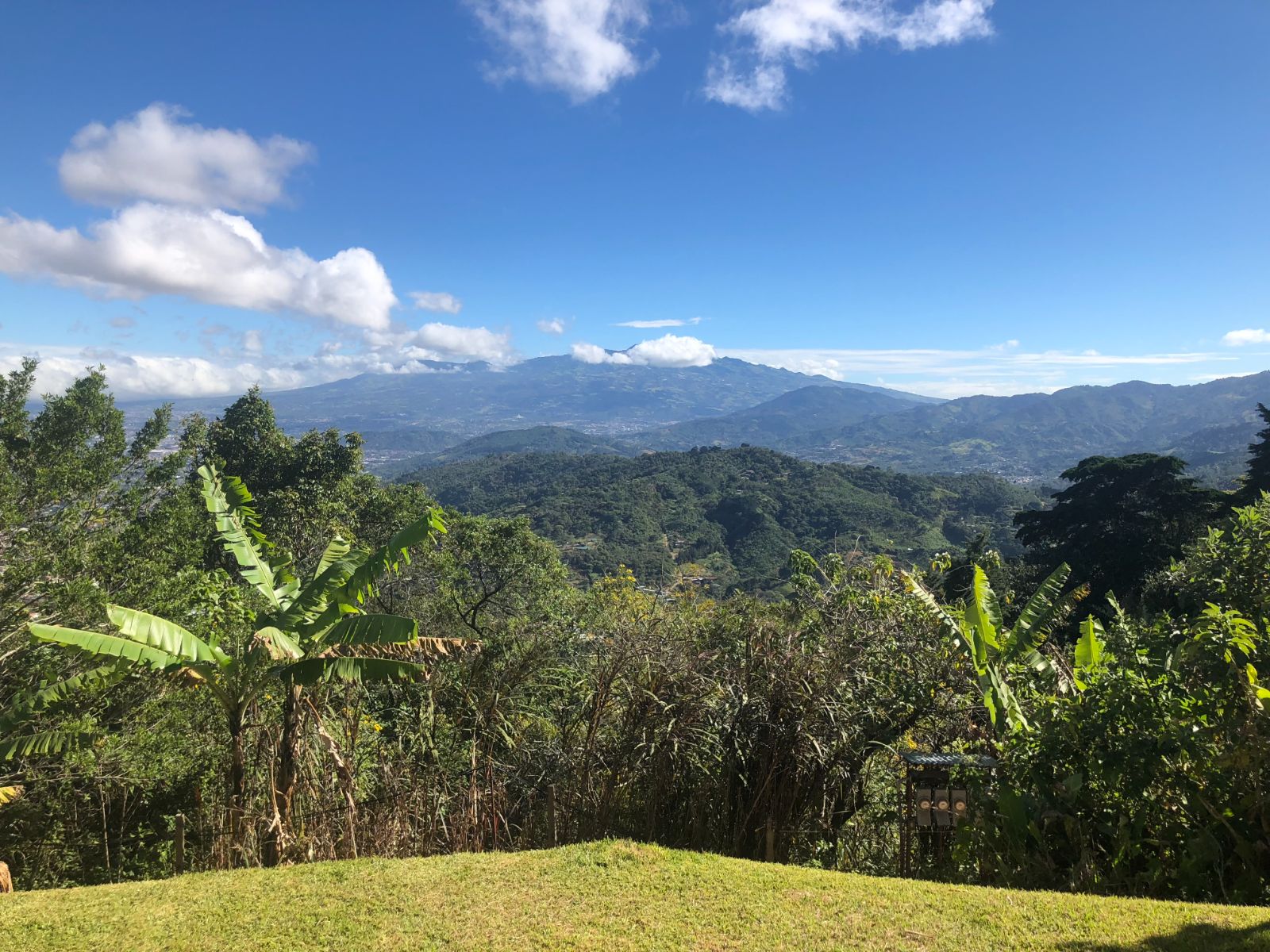 A sweeping view of green Costa Rica mountains under a blue sky