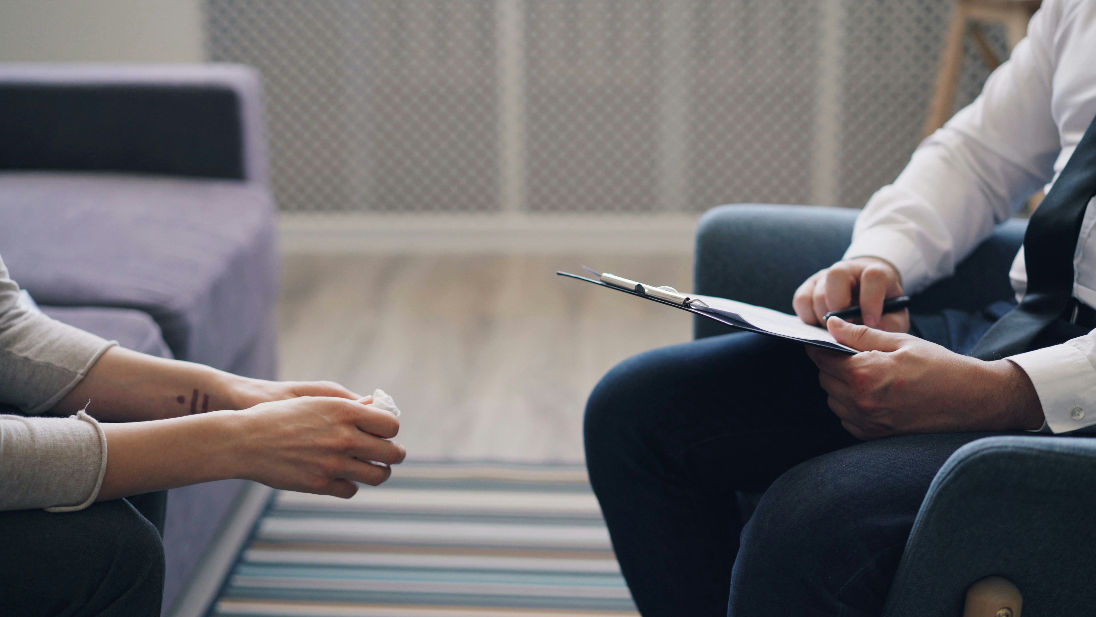 Therapist and client seated during a session, clipboard in hand